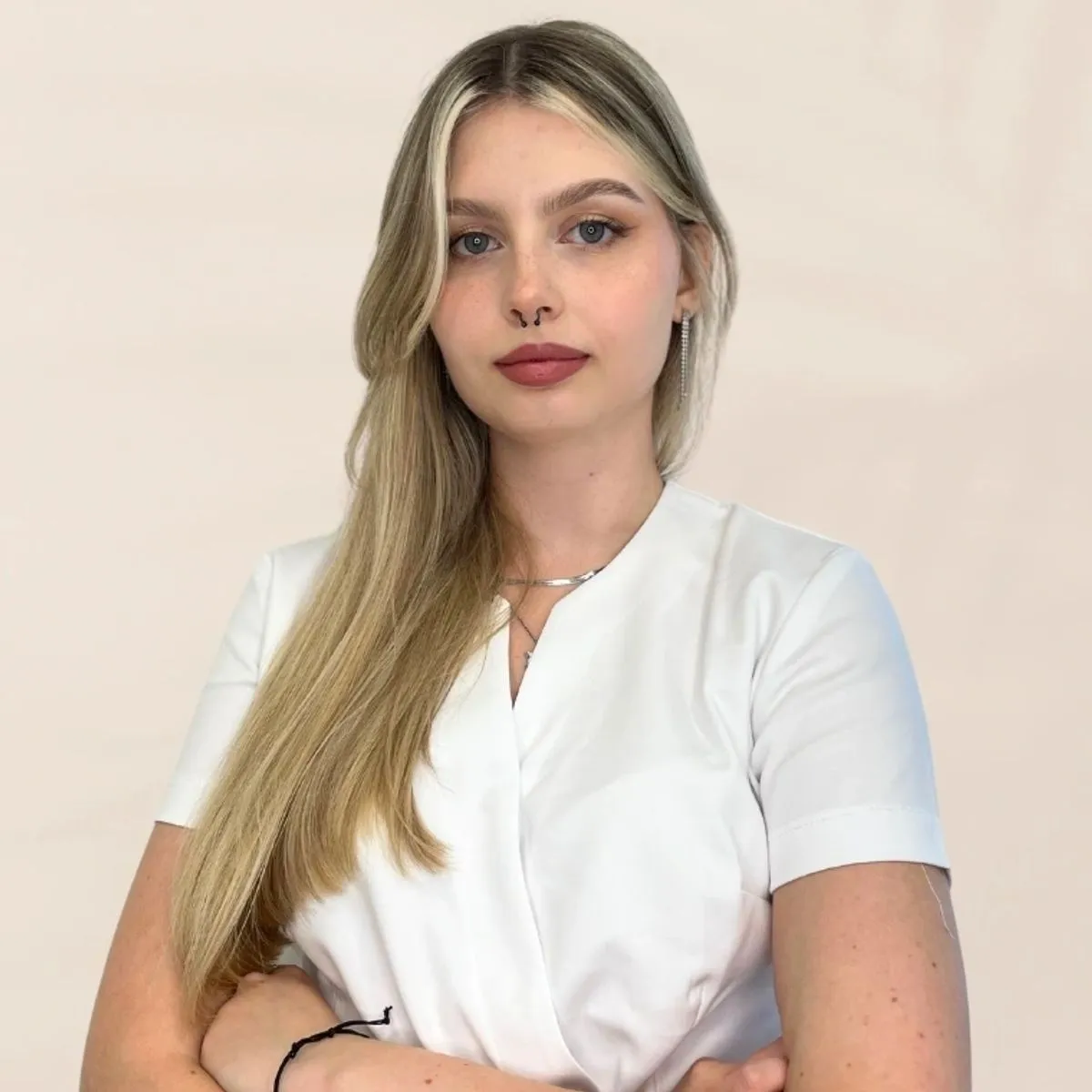 Młoda kobieta z długimi blond włosami w białym stroju.
